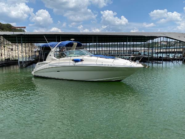 Sea Ray 320 Sundancer 2003 Sea Ray 320 Sundancer boat docked on calm water under a blue sky.