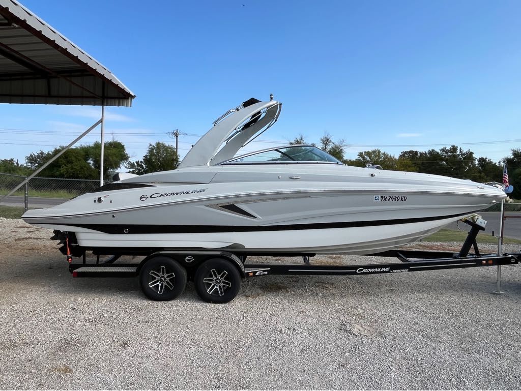 Crownline E275 2023 Crownline E275 boat on trailer, parked outdoors under a canopy.