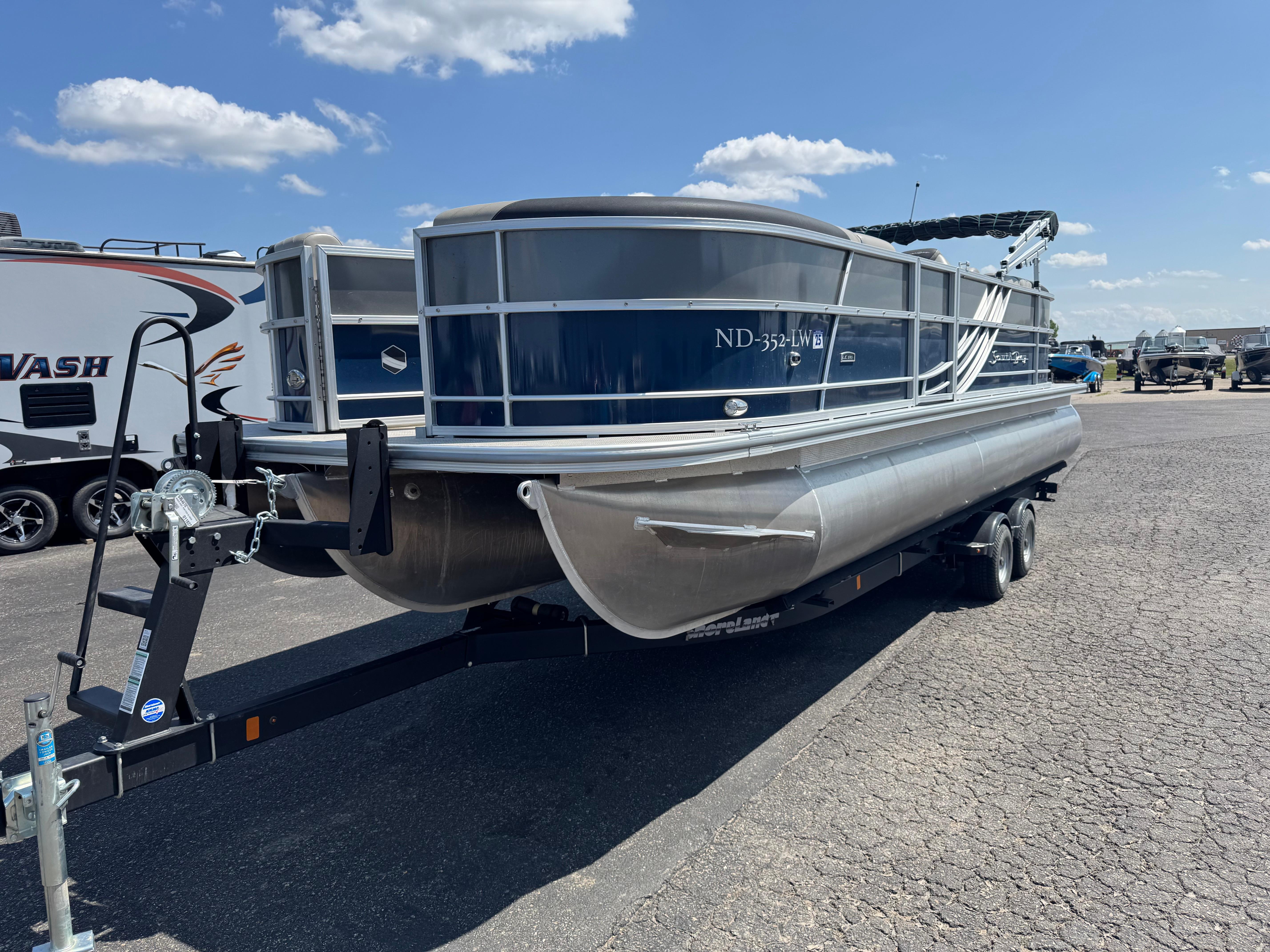 South Bay 224RS LE 2.75 Tritoon 2023 South Bay 224RS LE 2.75 Tritoon on trailer under blue sky.