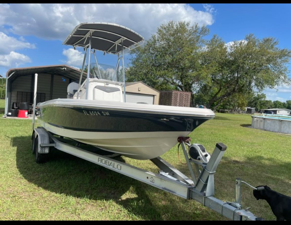 Robalo 206 Cayman 2018 Robalo 206 Cayman boat on trailer, parked on grassy lawn under blue sky.