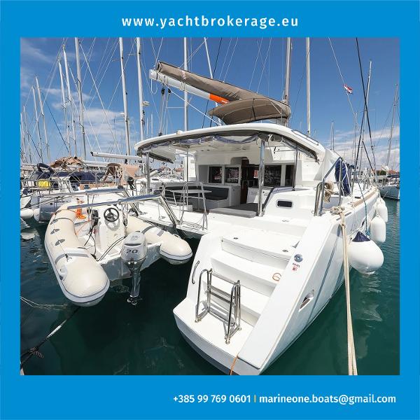 Lagoon 450 FLY 2014 Lagoon 450 FLY yacht docked with inflatable boat, sunny marina setting.