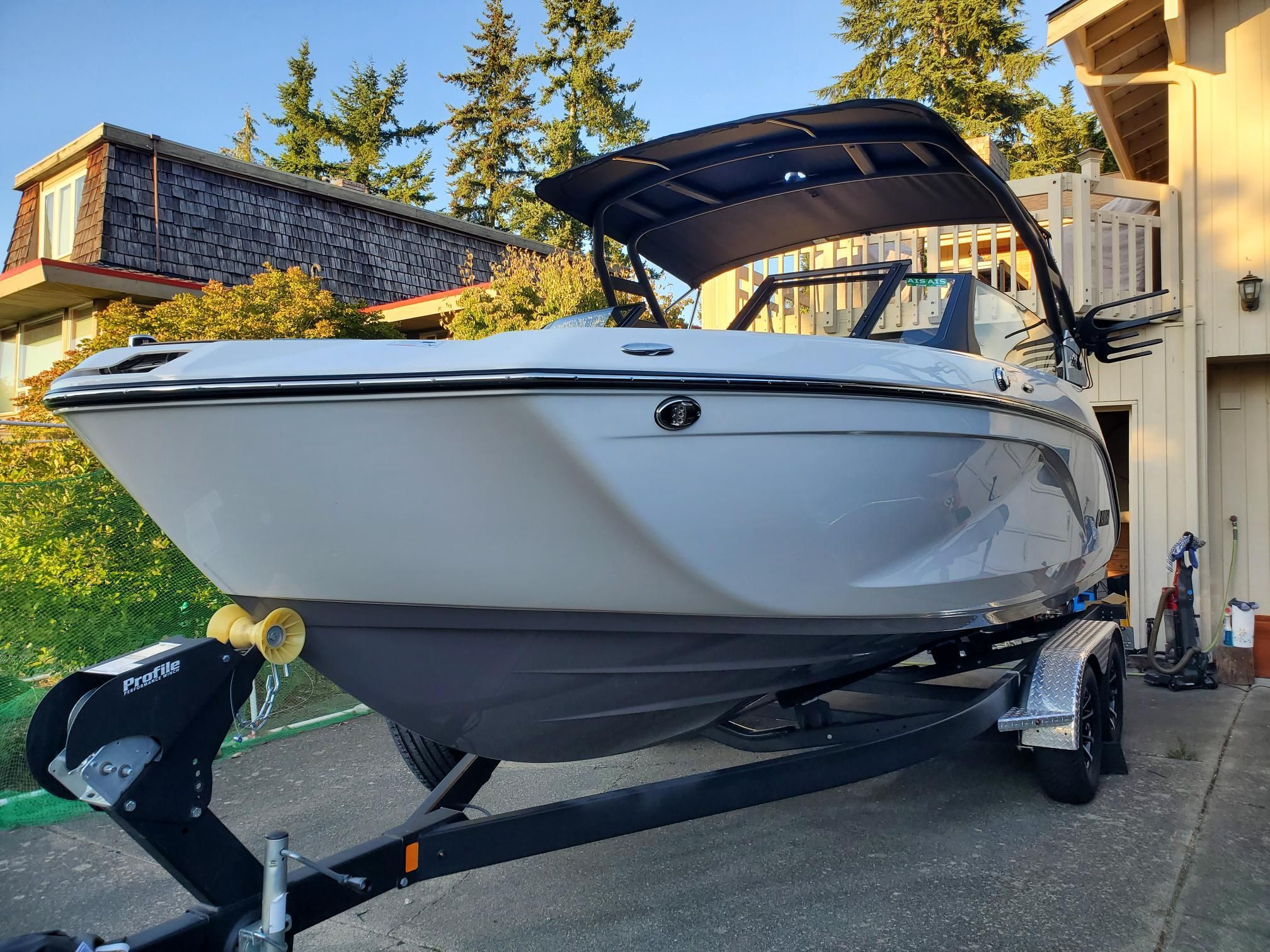Yamaha Boats 222SD 2023 Yamaha Boats 222SD on trailer, parked in residential driveway with trees in background.