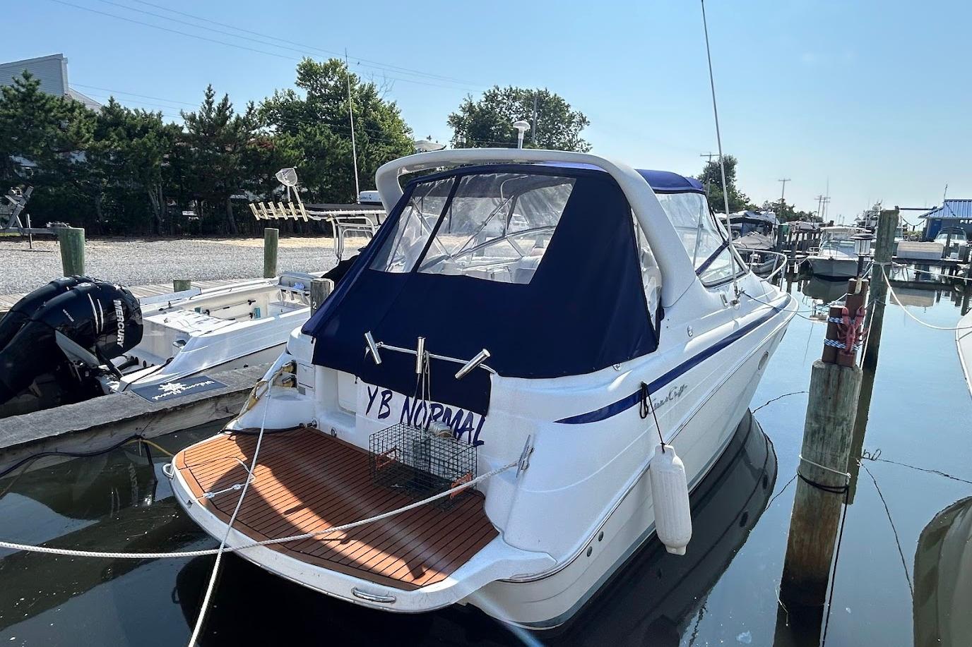 Chris-Craft 320 Express Cruiser 1998 Chris-Craft 320 Express Cruiser docked at marina, featuring blue canopy and wooden deck.
