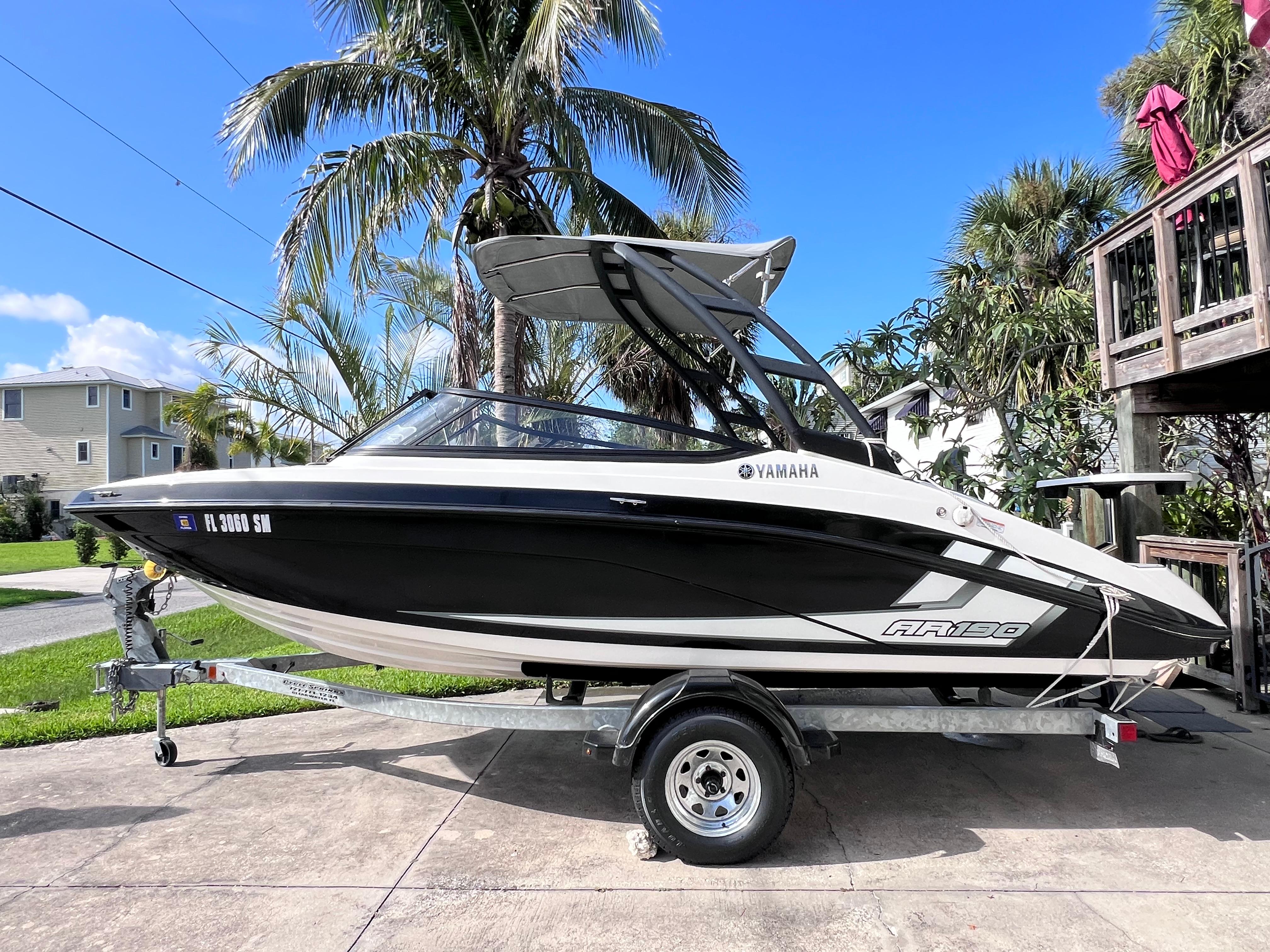 Yamaha Boats AR190 2019 Yamaha AR190 boat on trailer, parked near palm trees under clear blue sky.