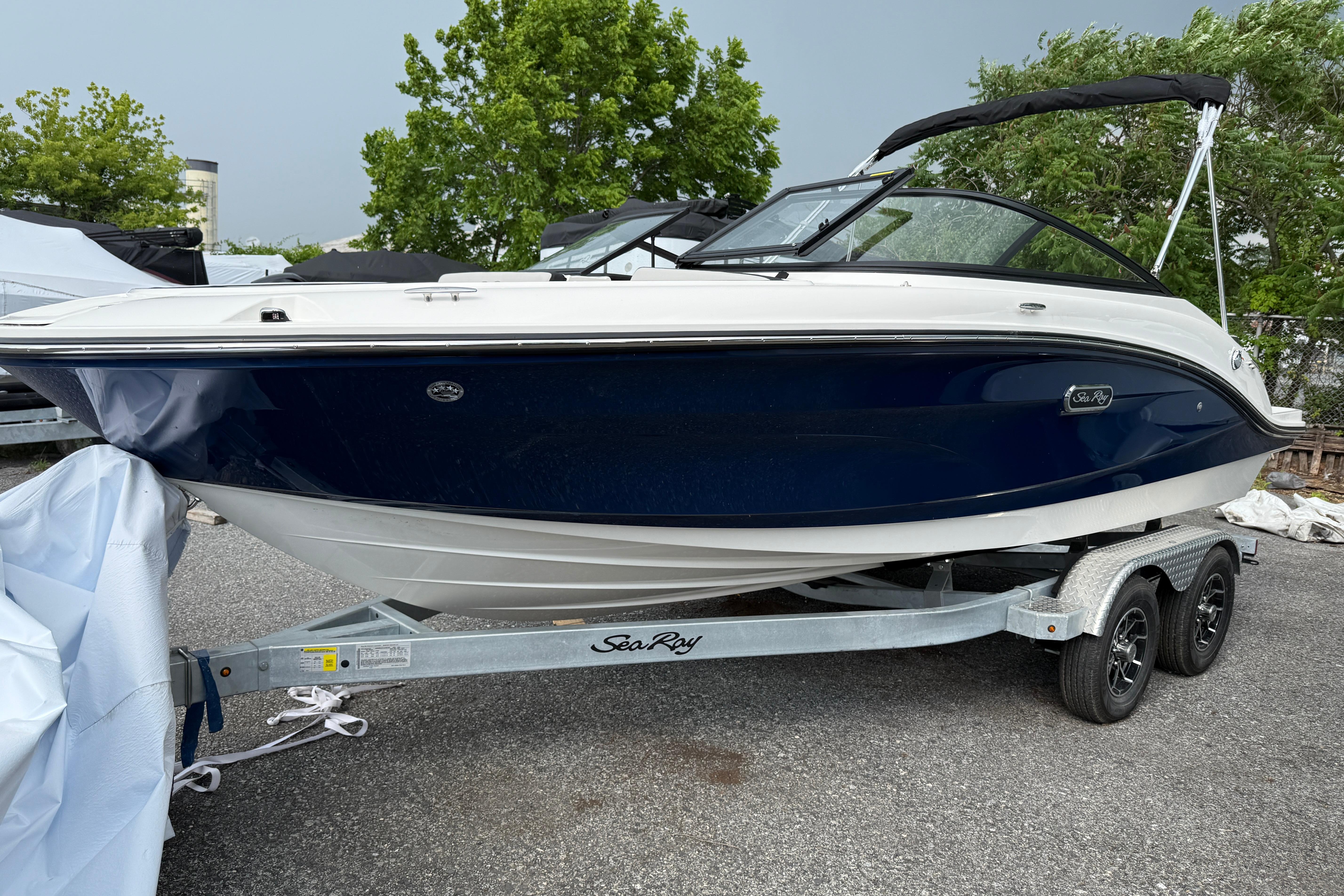 Sea Ray SPX 190 2025 Sea Ray SPX 190 boat on trailer, parked outdoors with trees in background.