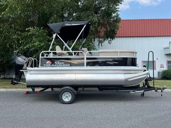 Sun Tracker Party Barge 16 DLX 2025 Sun Tracker Party Barge 16 DLX pontoon boat on trailer, parked outdoors.