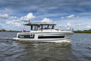 Jeanneau Merry Fisher 895 Marlin 2021 Jeanneau Merry Fisher 895 Marlin cruising on a scenic waterway under a partly cloudy sky.