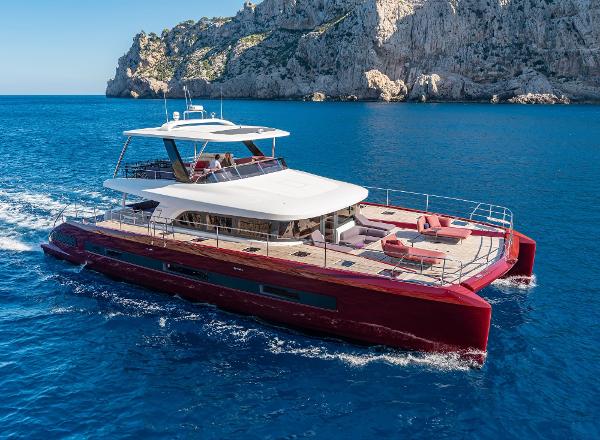 Lagoon SIXTY 7 Luxurious 2025 Lagoon SIXTY 7 yacht cruising in clear blue waters near rocky cliffs.