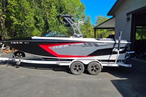 Tigé 22RZX 2021 Tigé 22RZX boat on trailer, parked outdoors with lush greenery background.