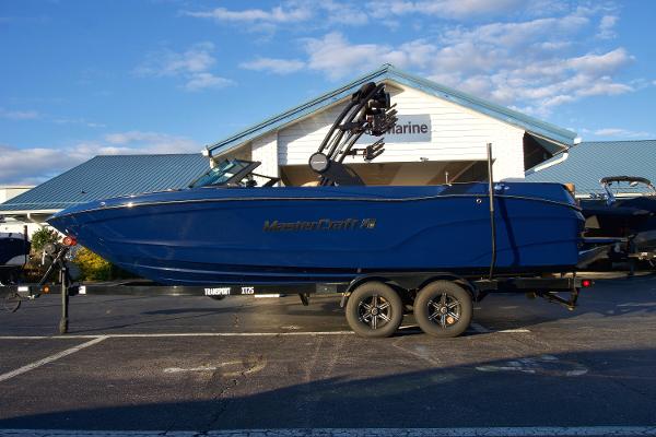MasterCraft XT25 2025 MasterCraft XT25 boat on trailer, parked outside a marine dealership.