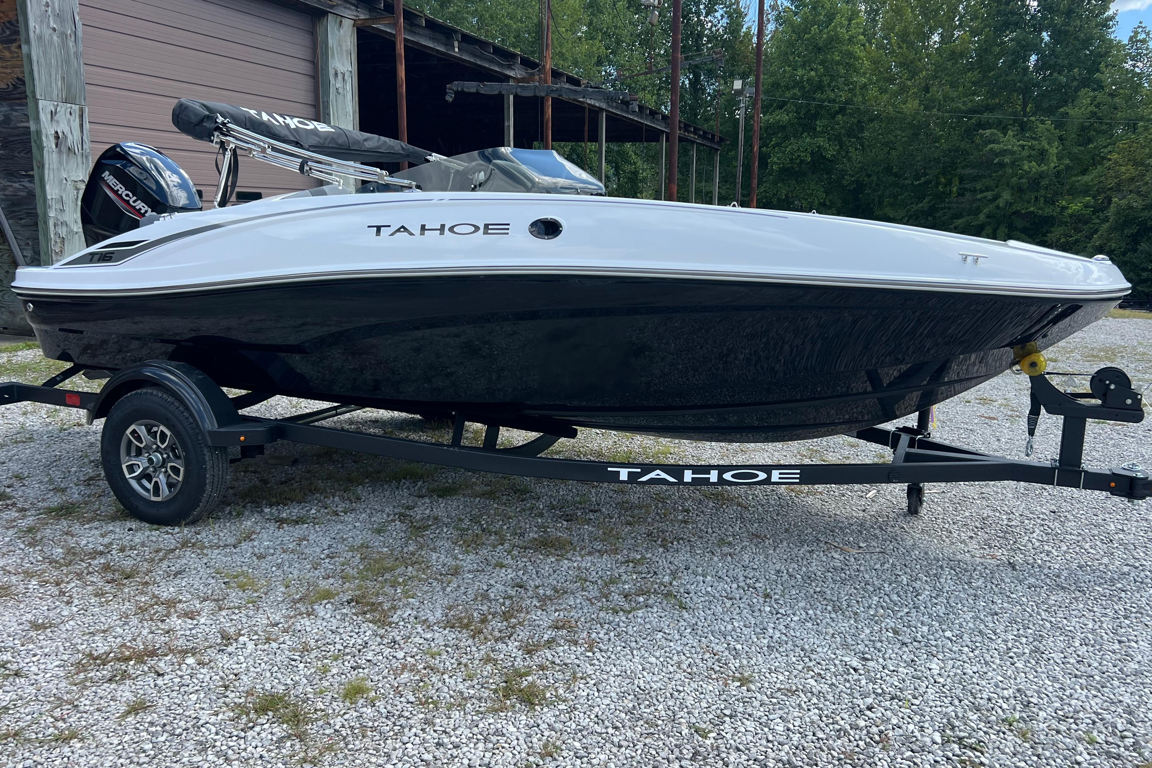 Tahoe T16 2026 Tahoe T16 boat on trailer, parked outdoors near a wooden building.