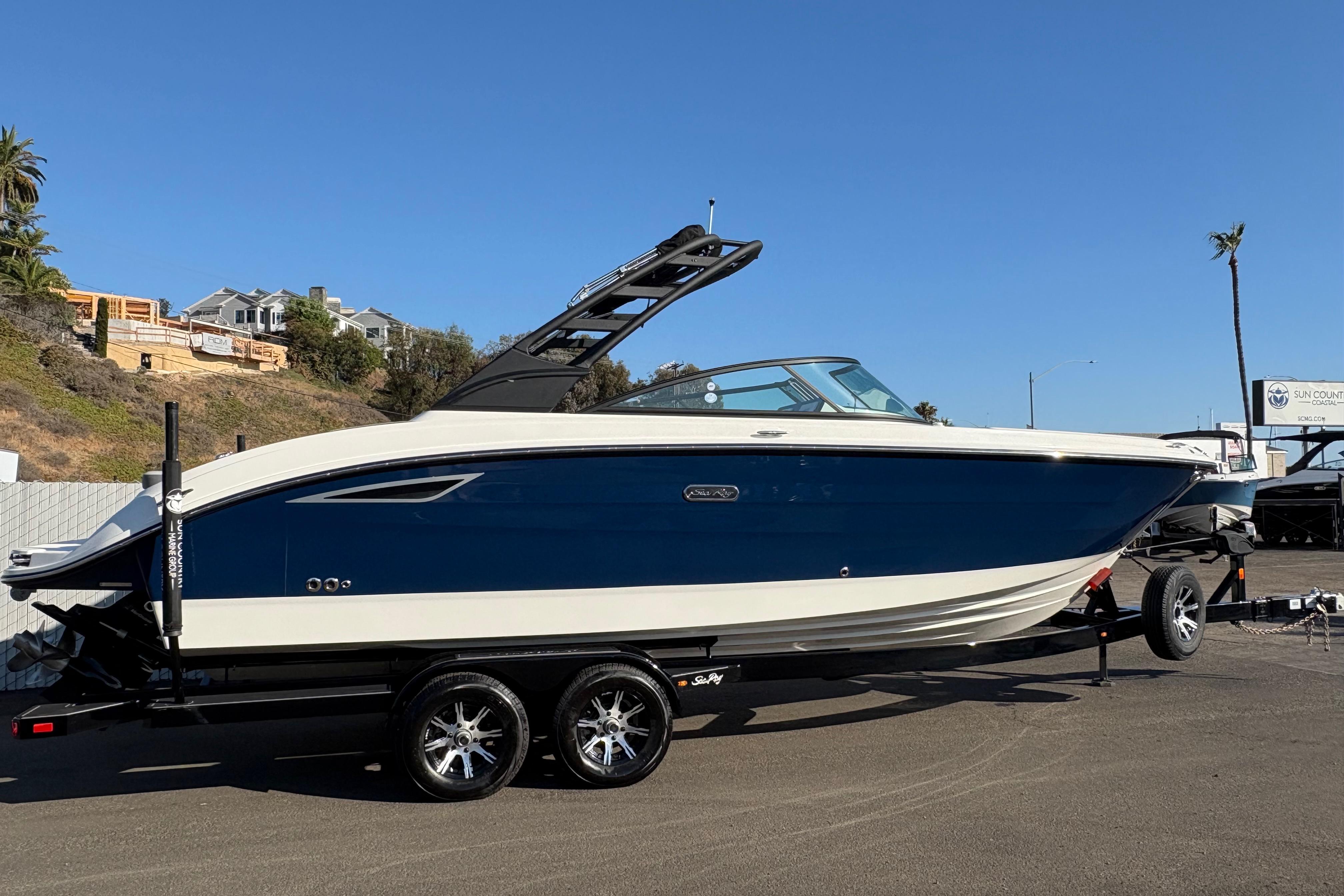 Sea Ray SDX 270 2025 Sea Ray SDX 270 boat on trailer, blue and white design, sunny day.
