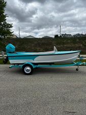 Starcraft 57 Ski Champ 2025 Starcraft 57 SKI CHAMP boat, turquoise and white, on a trailer, parked on a road.