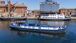 Dutch Barge 24m Luxemotor 1931 Dutch Barge 24m Luxemotor on a scenic river with historic buildings.