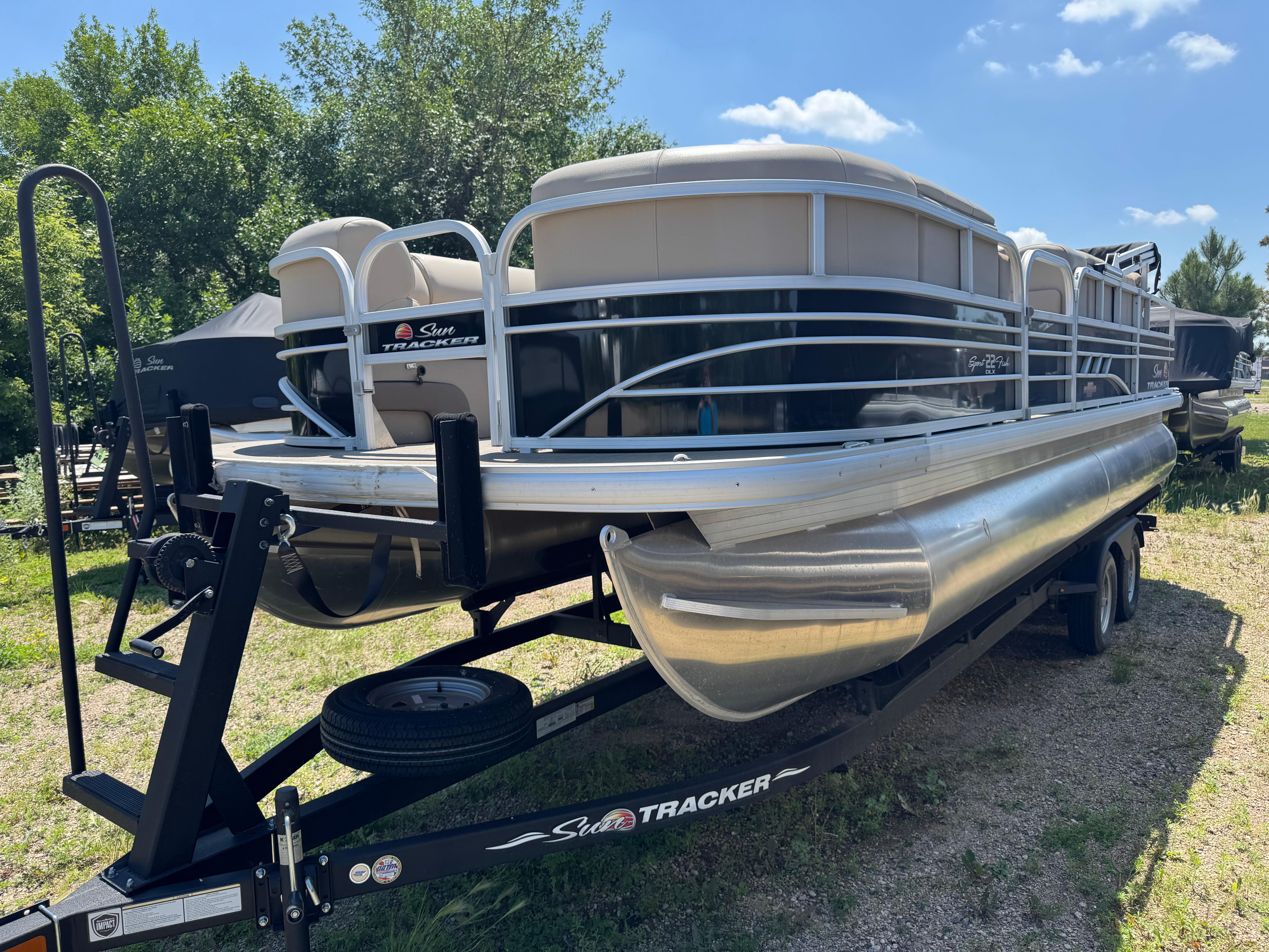 Sun Tracker SportFish 22 DLX 2023 Sun Tracker SportFish 22 DLX pontoon boat on trailer, parked outdoors.