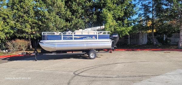 Sun Tracker Bass Buggy 18 DLX 2025 Sun Tracker Bass Buggy 18 DLX pontoon boat on trailer, parked outdoors.