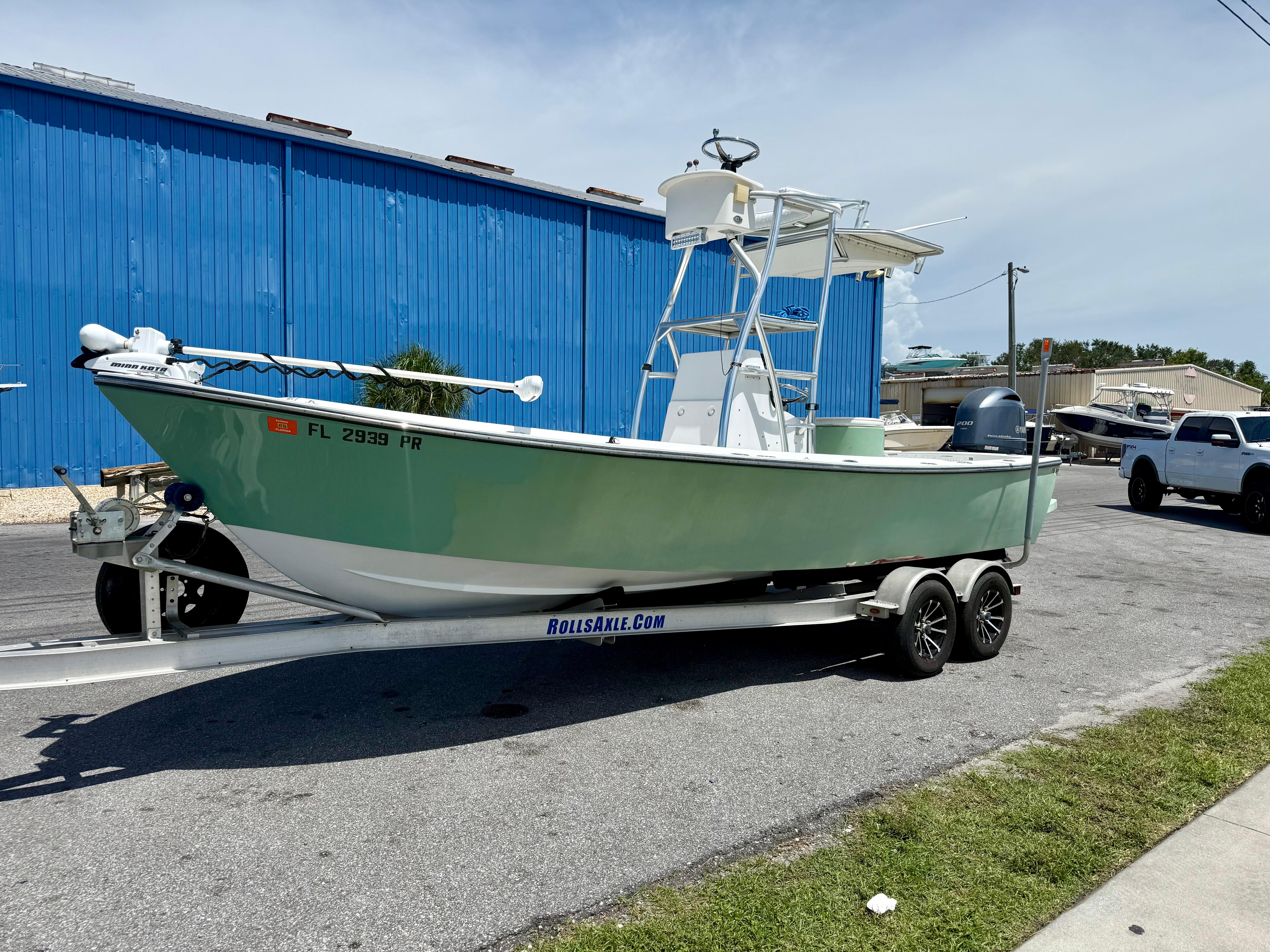 Aquasport 222 2014 Aquasport 222 boat on trailer, parked near blue building, sunny day.