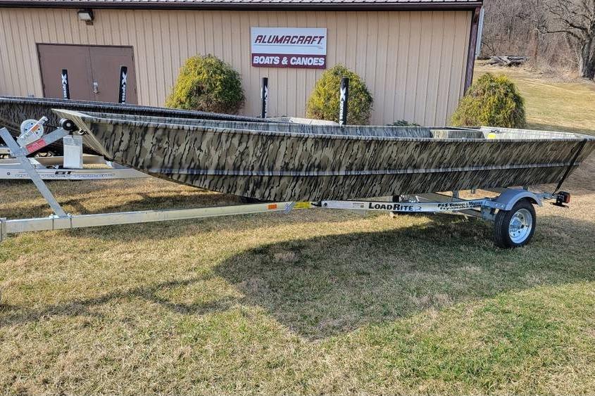 Smoker Craft 1648 jon boat, 20" transom with trailer 2025 Smoker Craft 1648 jon boat on trailer, parked on grass near Alumacraft building.