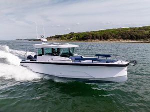 Axopar 29 XC Cross Cabin - 25% share 2025 Axopar 29 XC Cross Cabin cruising on open water near a forested shoreline.