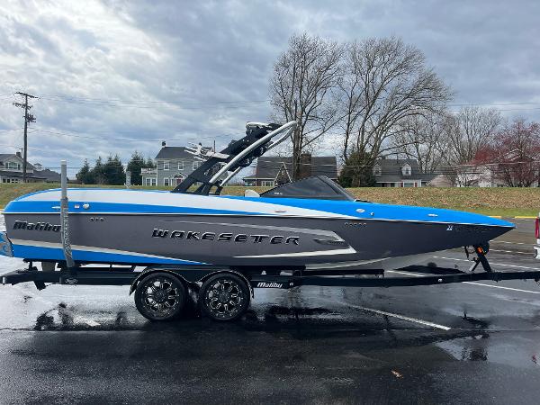Malibu Wakesetter 24 MXZ 2014 Malibu Wakesetter 24 MXZ boat on trailer, blue and gray design, parked outdoors.