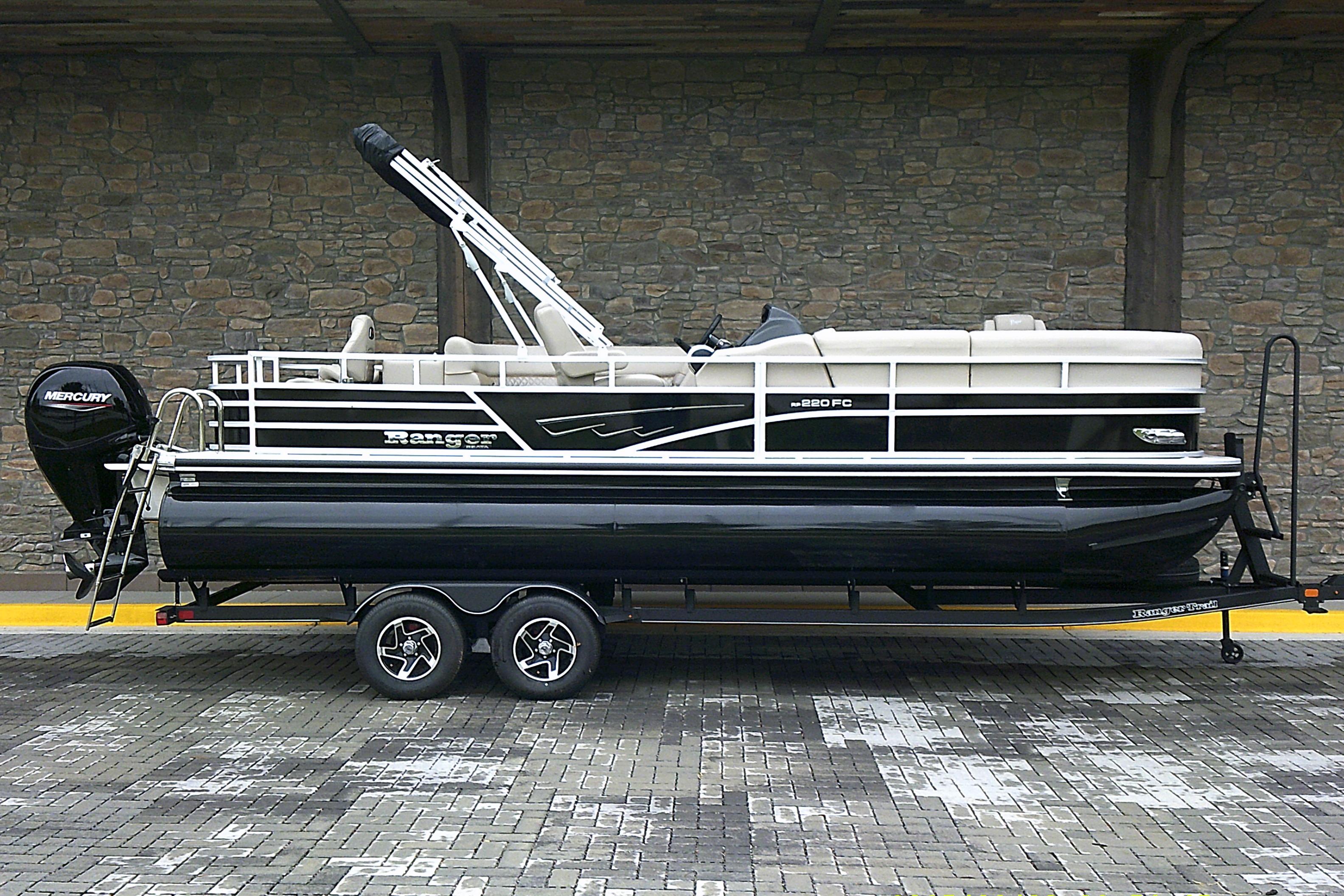 Ranger Reata 220FC 2025 Ranger Reata 220FC pontoon boat on trailer, parked against stone wall.