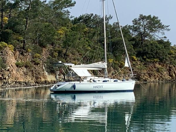 Custom Cybelle 25 Sailboat "Mardek" anchored in a serene bay, surrounded by lush trees.