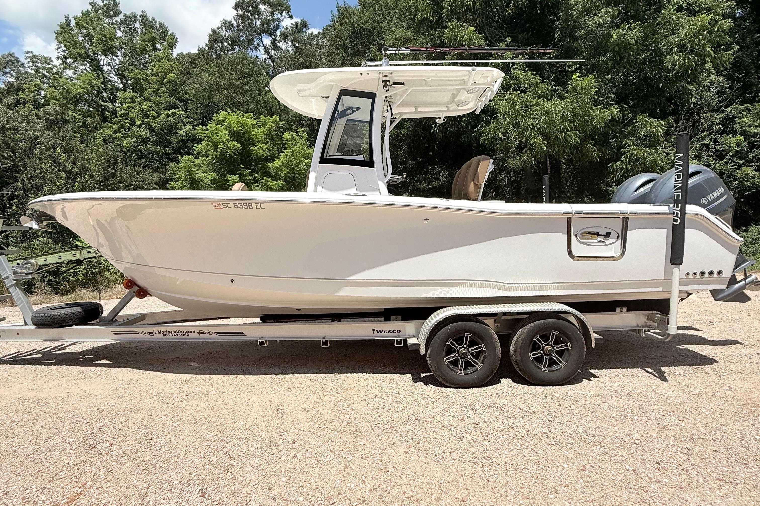 Sea Hunt Gamefish 25 2023 Sea Hunt Gamefish 25 boat on trailer, surrounded by trees.