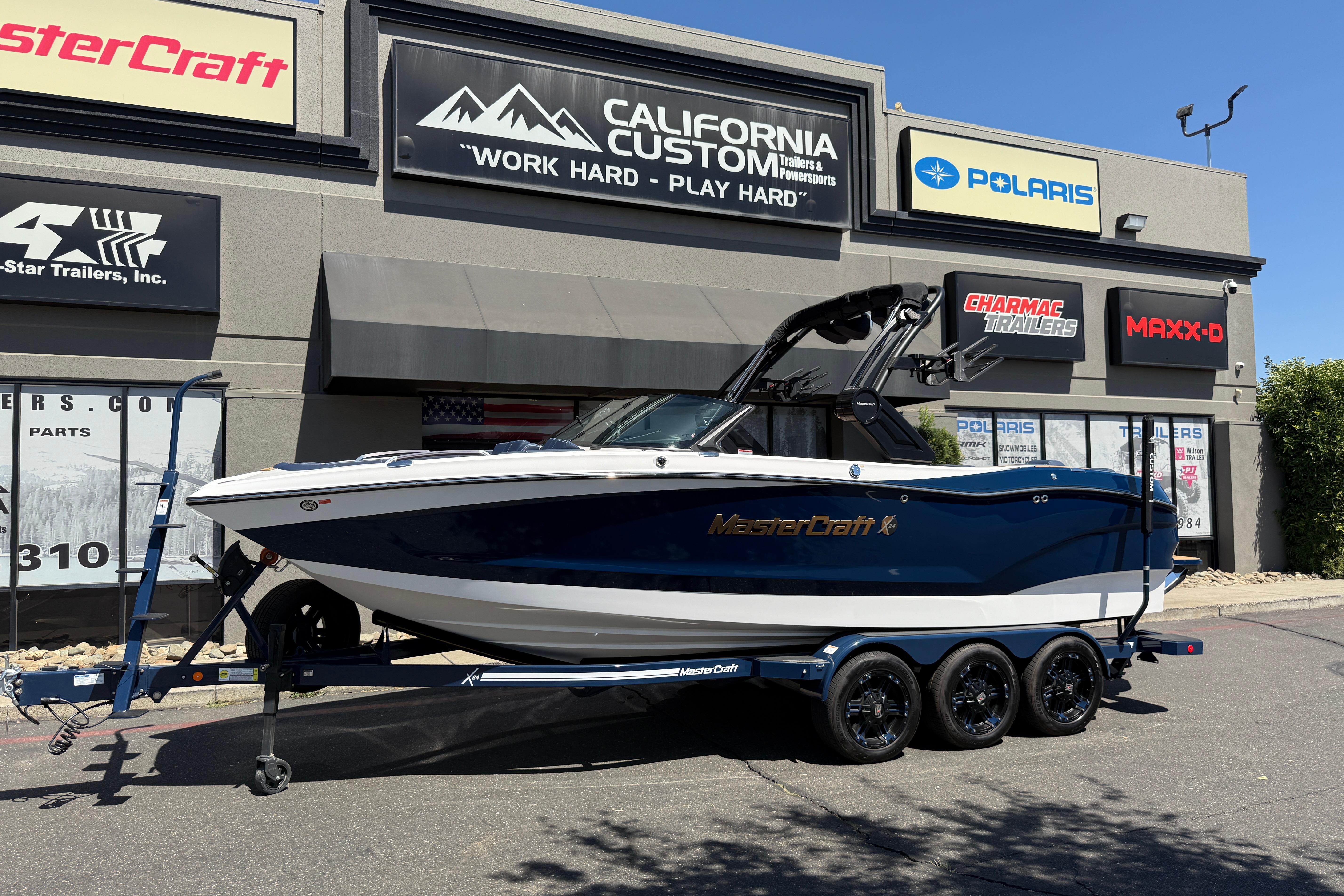 MasterCraft X24 2024 MasterCraft X24 boat on trailer outside California Custom showroom.