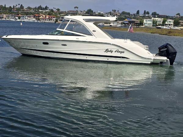 Sea Ray SLX 310 Outboard 2023 Sea Ray SLX 310 OB boat on calm water, with coastal background.
