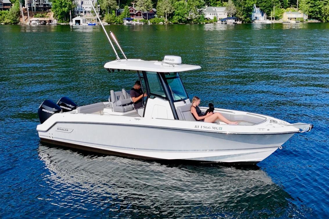 Boston Whaler 250 Outrage 2024 Boston Whaler 250 Outrage boat on a serene lake with passengers.