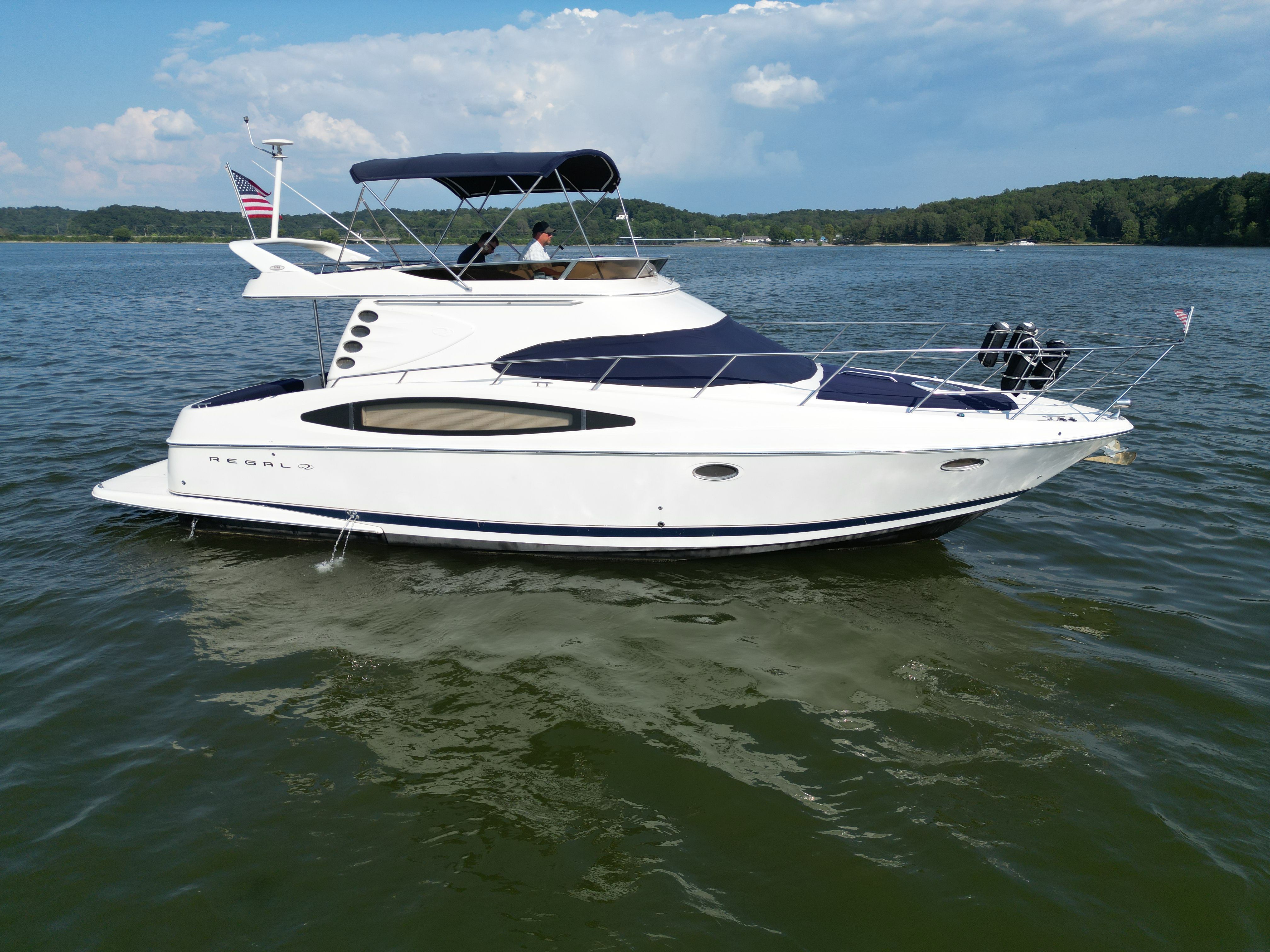 Regal Commodore 3780 2001 Regal Commodore 3780 yacht cruising on a serene lake under a clear sky.