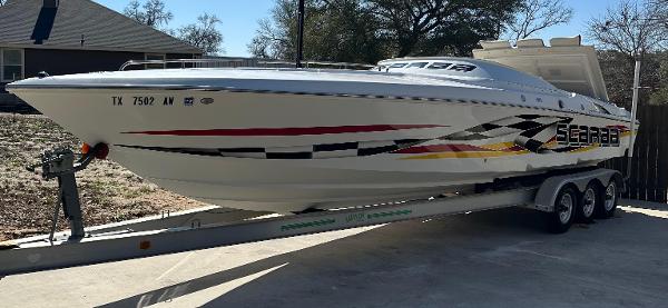 Wellcraft Scarab 33 2000 Wellcraft Scarab 33 AVS speedboat on trailer, featuring vibrant graphics.