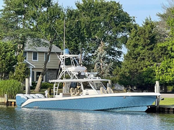 Everglades 435 CC 2019 Everglades 435 CC boat docked by a waterfront home, surrounded by lush greenery.