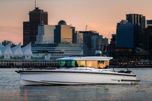 Axopar 37 XC 2024 Axopar 37 XC boat cruising near city skyline at sunset.