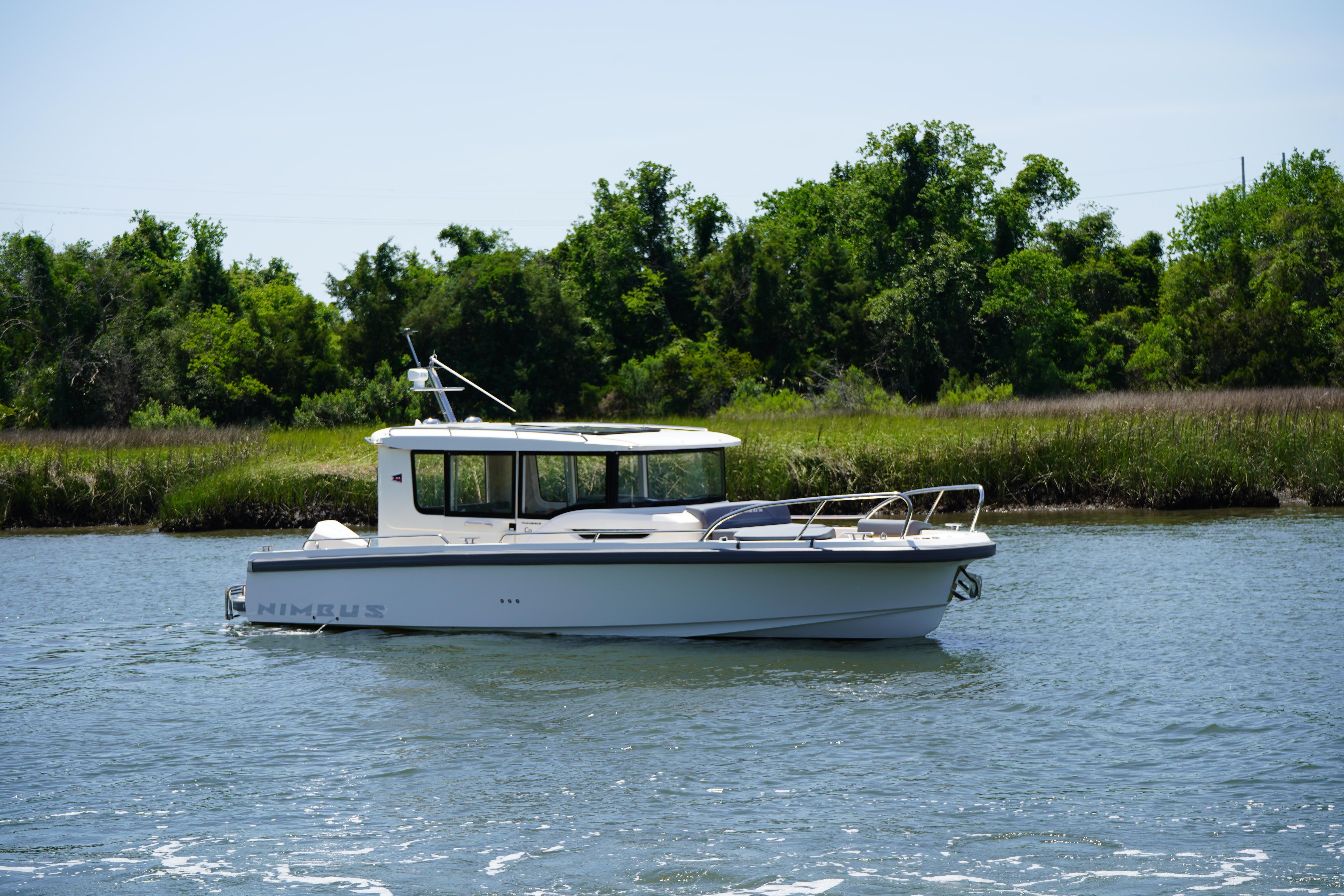 Nimbus Commuter9 C9 2024 Nimbus Commuter9 C9 boat cruising on a serene river with lush greenery.