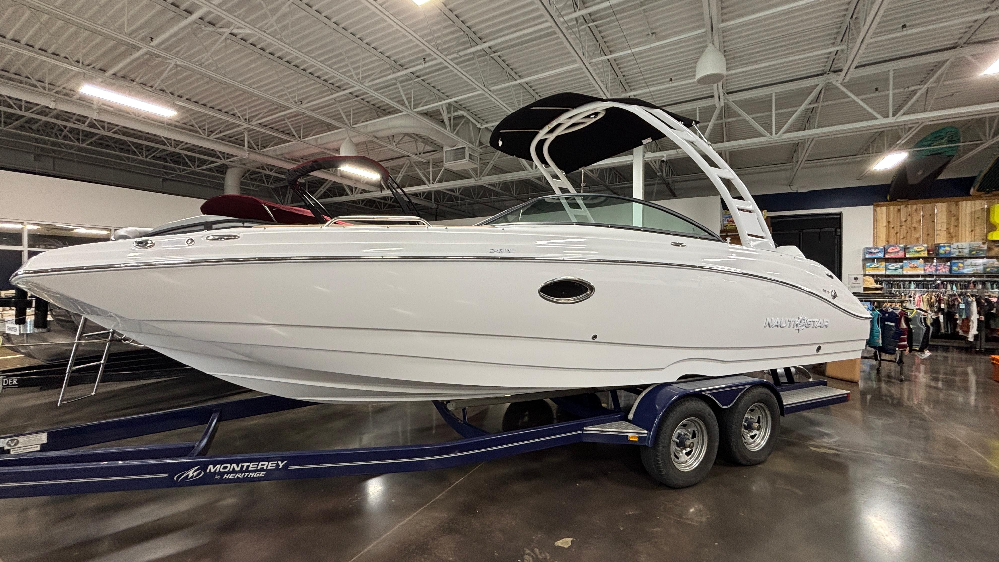 NauticStar 243 DC Deck 2025 NauticStar 243 DC Deck boat on trailer in showroom setting.