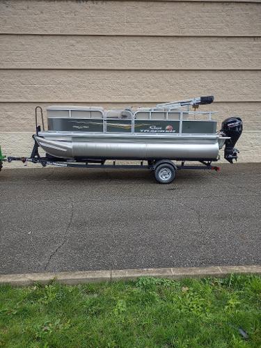 Sun Tracker Party Barge 18 DLX 2025 Sun Tracker Party Barge 18 DLX pontoon boat on trailer, parked outdoors.