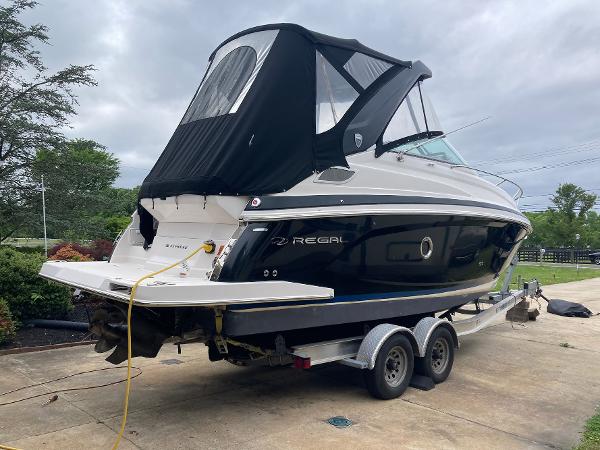 Regal 28 Express 2015 Regal 28 Express boat on trailer, black canopy, parked outdoors.