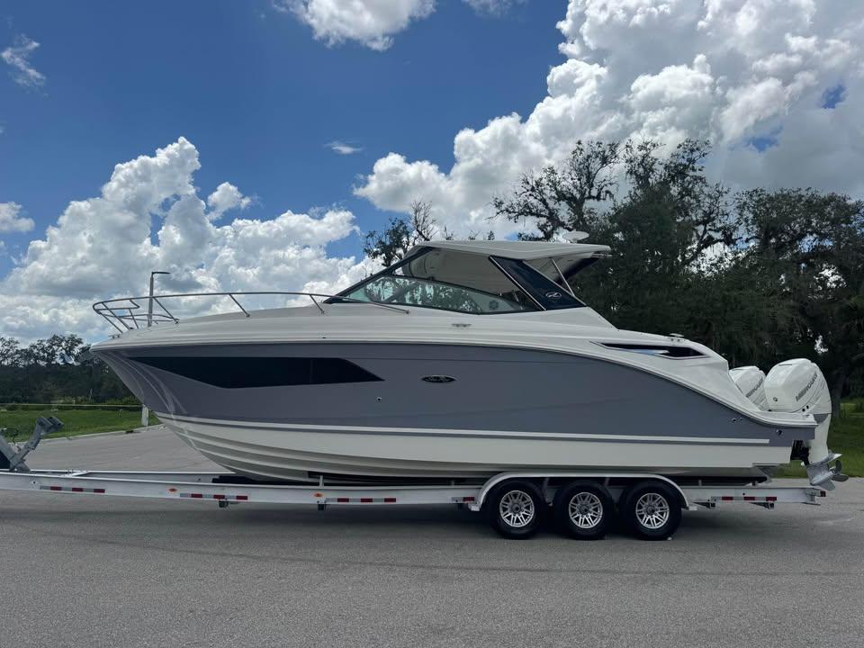 Sea Ray Sundancer 320 Outboard 2023 Sea Ray Sundancer 320 Outboard on trailer, under a partly cloudy sky.