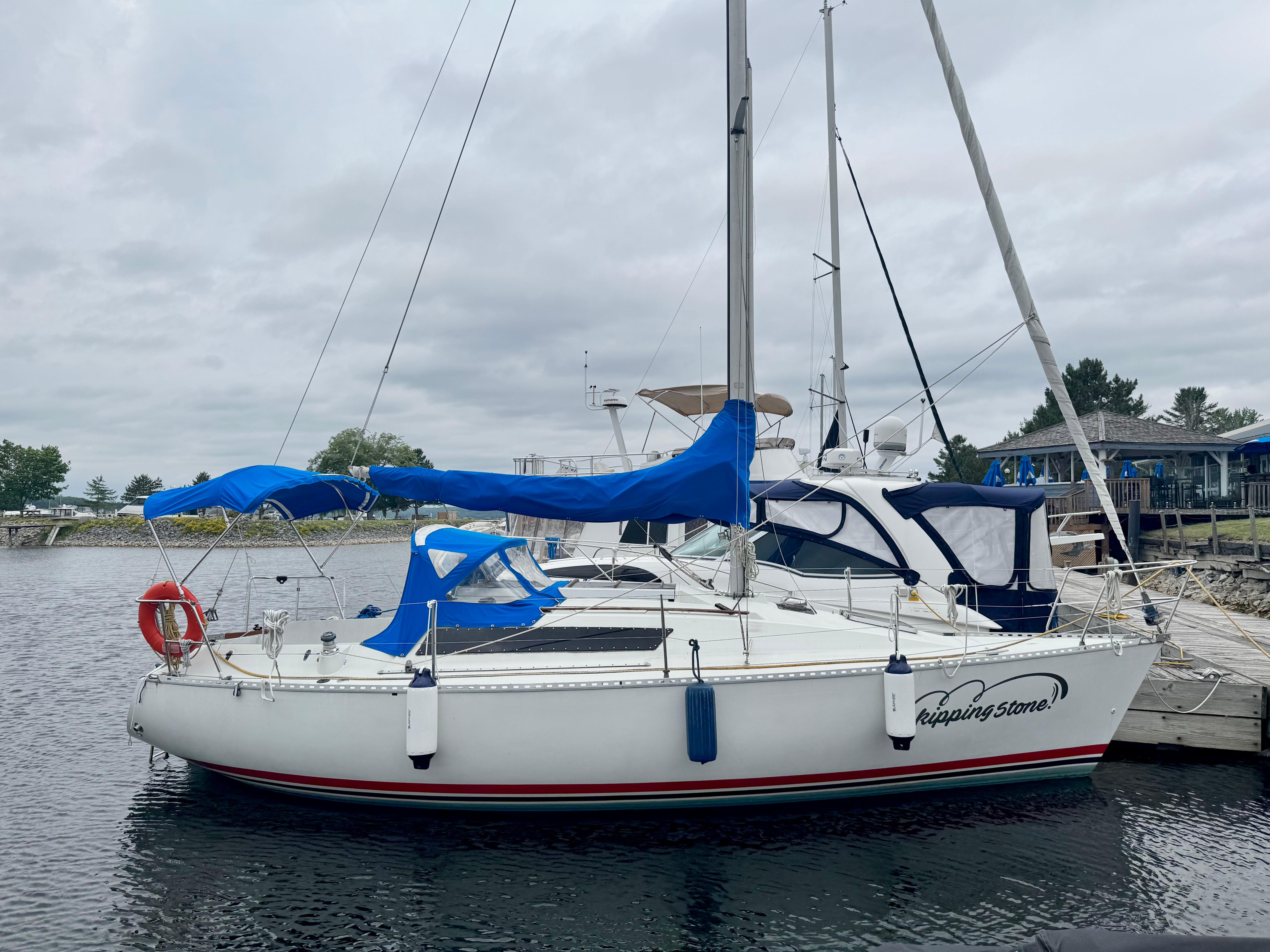 Beneteau First 29 1985 Beneteau First 29 sailboat docked, featuring blue covers and a calm marina setting.