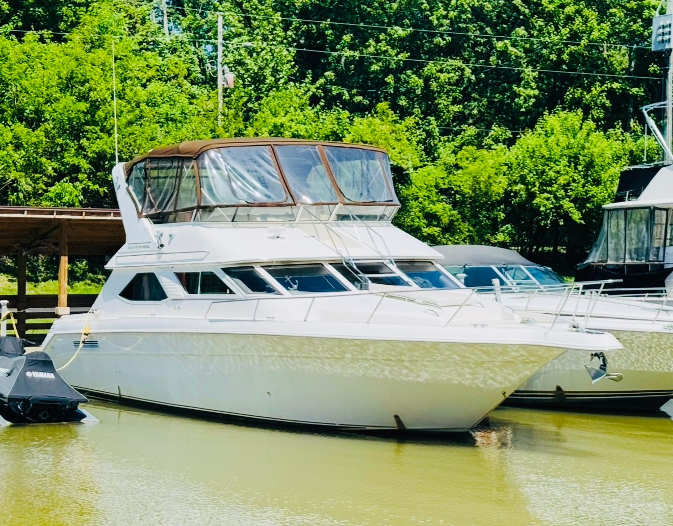 Sea Ray Express Bridge 440 1997 Sea Ray Express Bridge 440 yacht docked on calm water, surrounded by lush greenery.