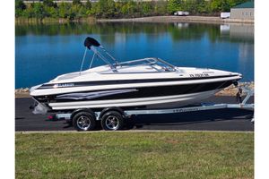 Larson LXi 228 2007 Larson LXi 228 boat on trailer by a lake, ready for transport.