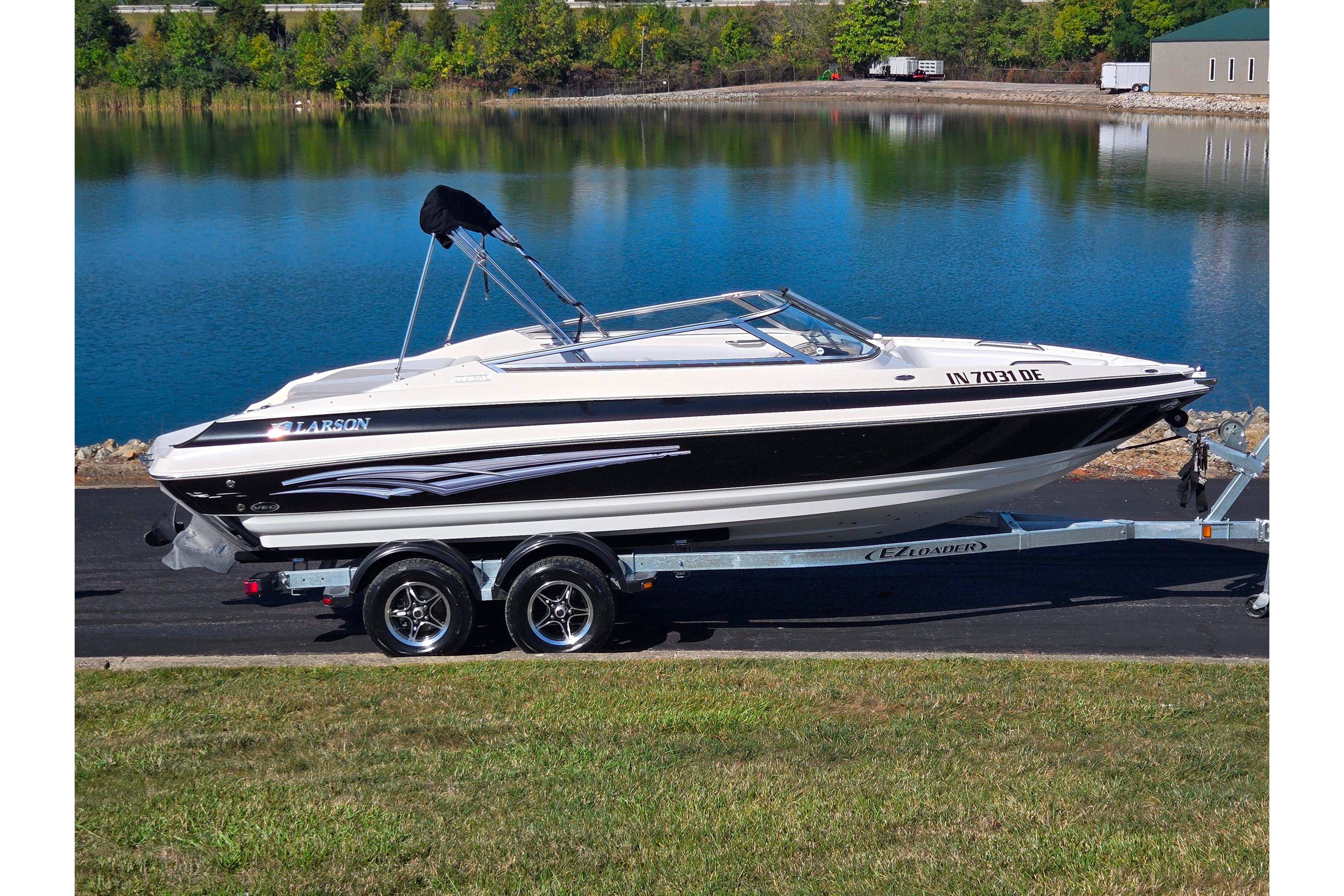 Larson LXi 228 2007 Larson LXi 228 boat on trailer by a lake, ready for transport.