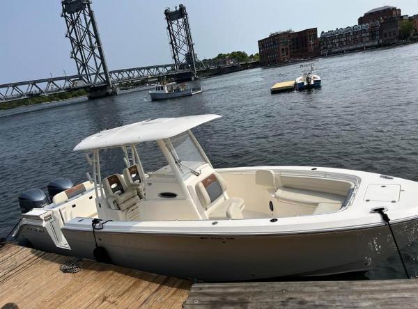 Cobia 301CC 2019 Cobia 301CC boat docked near a bridge on a sunny day.