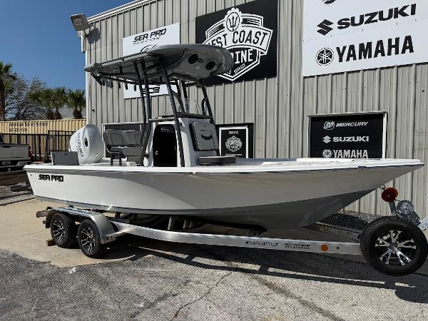 Sea Pro 210 Bay 2025 Sea Pro 210 Bay boat on trailer, parked outside dealership with Suzuki and Yamaha signage.