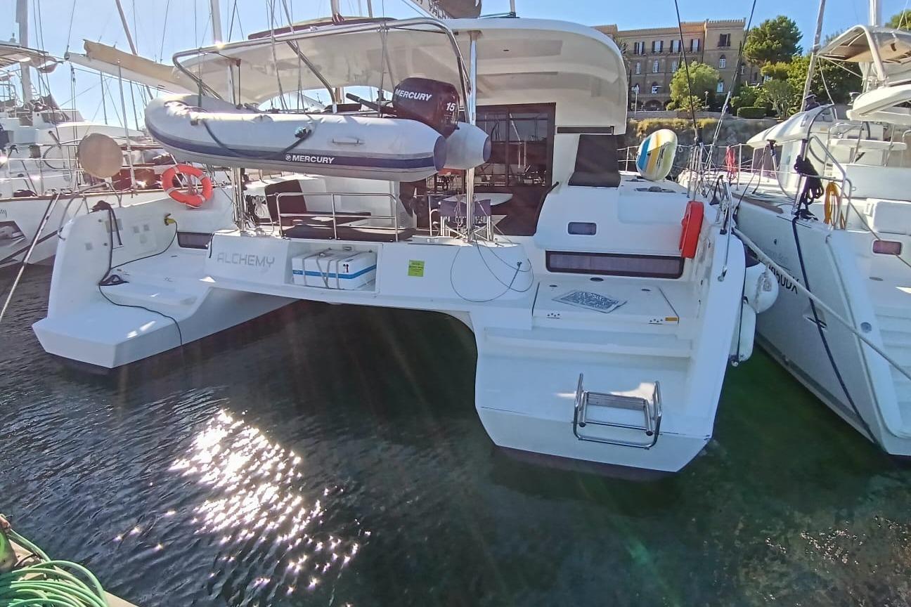 Lagoon 42 2019 Lagoon 42 catamaran docked, featuring a Mercury dinghy and spacious deck area.