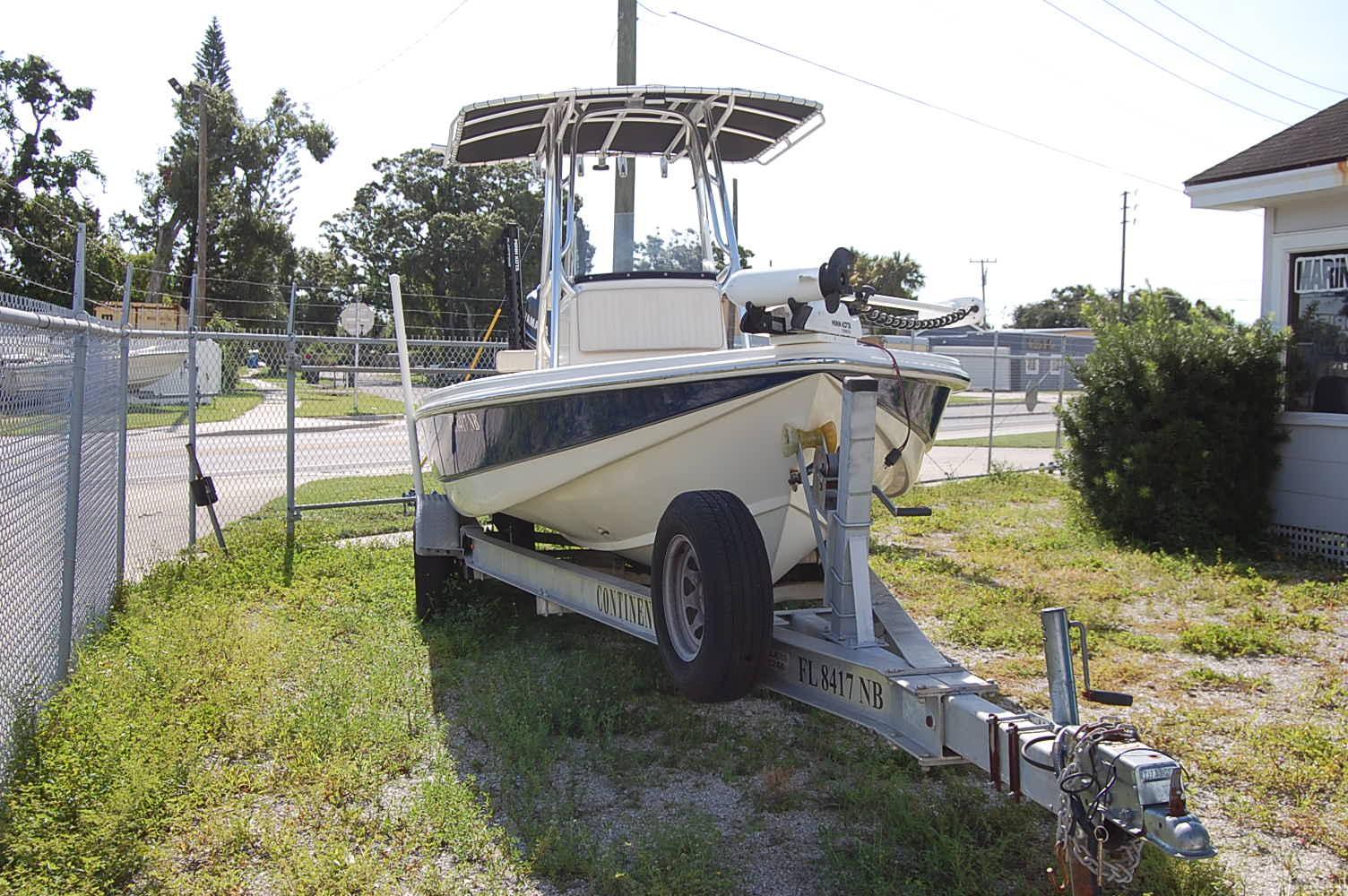 Scout 240 2006 Scout 240 boat on trailer parked outdoors near fence and building.