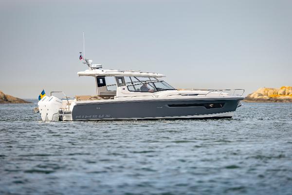 Nimbus W11 2025 Nimbus W11 boat cruising on calm waters near rocky shoreline.