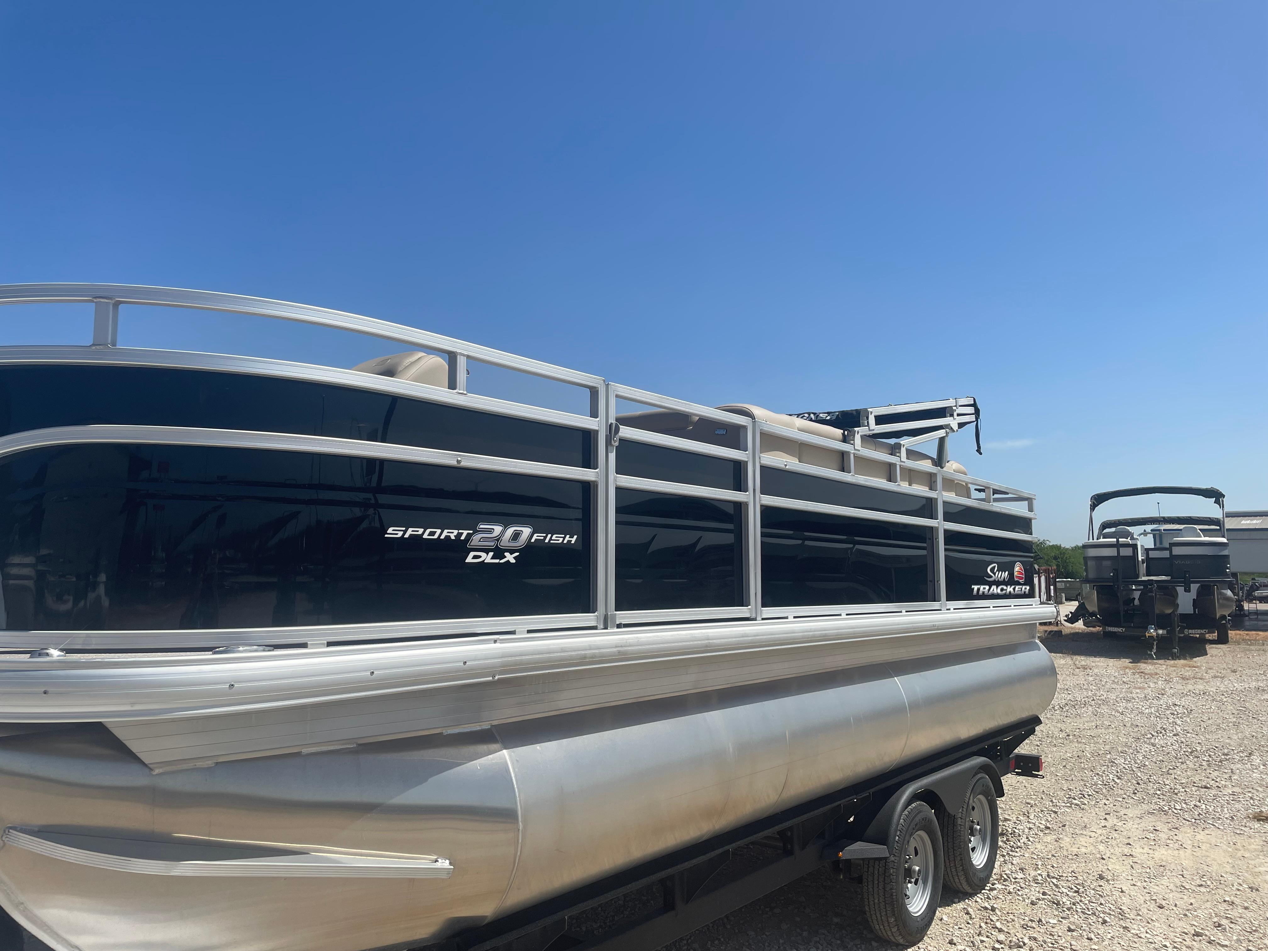 Sun Tracker SportFish 20 DLX 2025 Sun Tracker SportFish 20 DLX pontoon boat on trailer under clear blue sky.