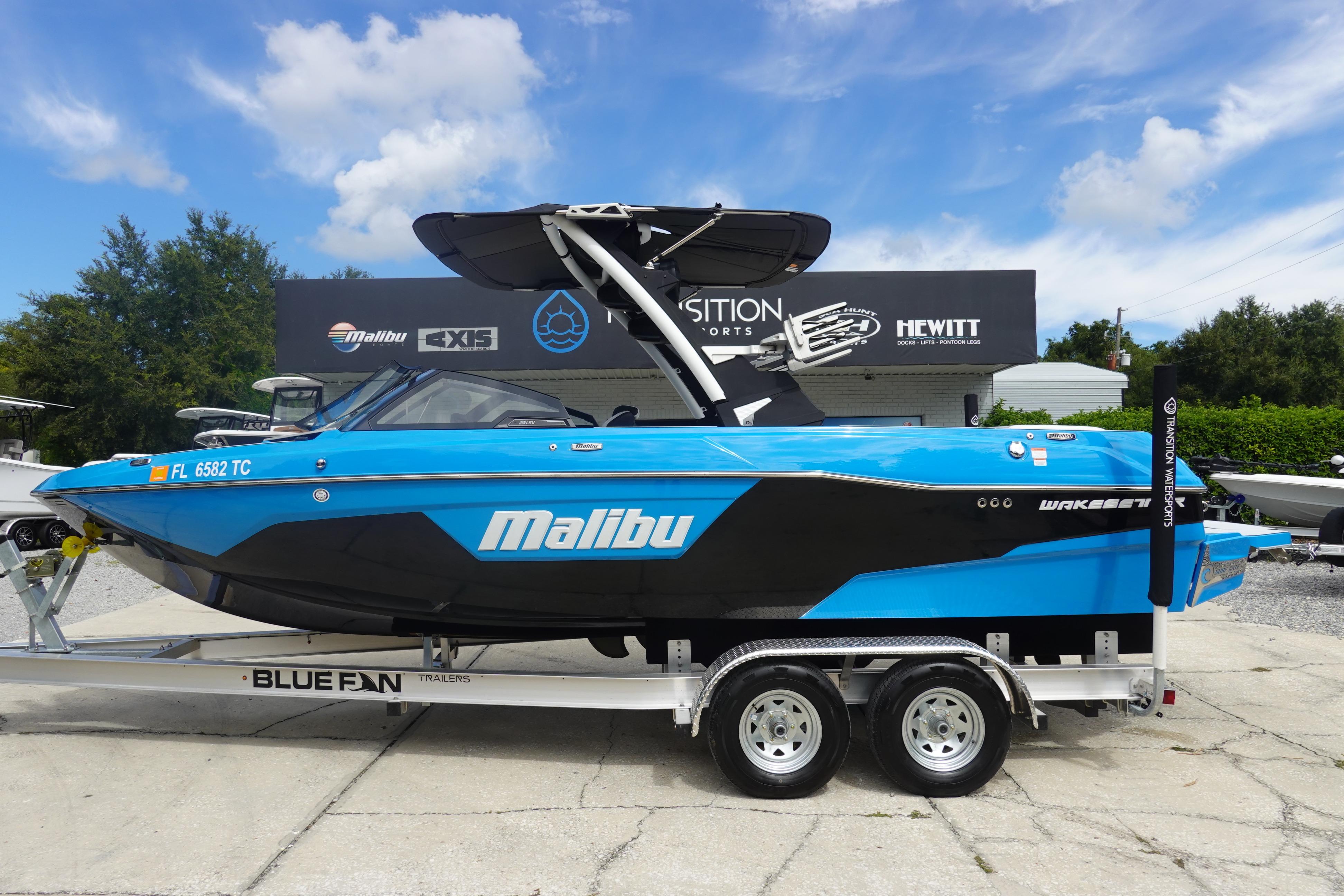 Malibu Wakesetter 23 LSV 2022 Malibu Wakesetter 23 LSV boat on trailer, displayed outdoors under blue sky.